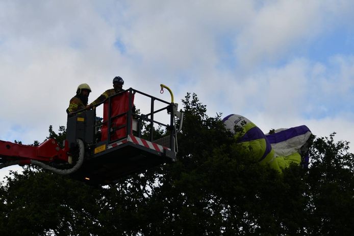 De brandweer probeert met behulp van een hoogwerker de parachute uit de boom te halen.