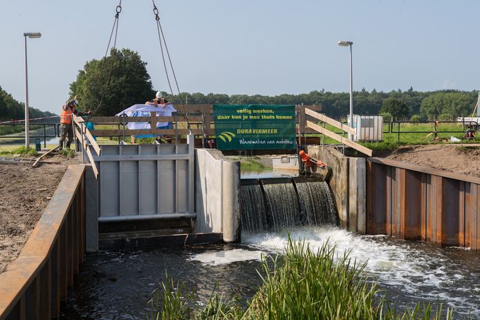 De stuwklep wordt met een kraan op zijn plek gehesen. Na de bouwvak is de andere kant van de stuw aan de beurt.