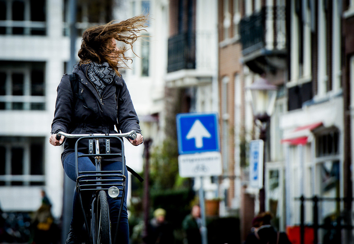 Een vrouw trotseert op haar fiets de wind in Amsterdam Beeld ANP