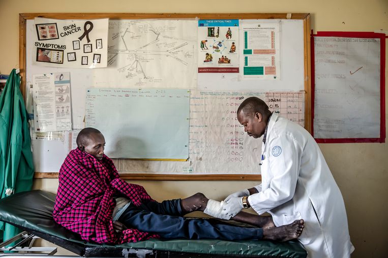  De arts Juma Olesampuerap verbindt het been van Partalala, de Masai die een schotwond opliep toen Tanzaniaanse agenten begin juni zijn dorp binnenvielen. Beeld Luis Tato voor de Volkskrant