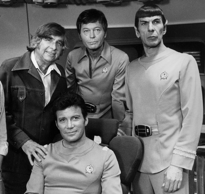Bedenker van de SF-serie, Gene Roddenberry. Naast hem leden van de cast: William Shatner, DeForest Kelley en Leonard Nimoy, alle drie in Star Trek-plunje, mét het bekende logo als insigne.