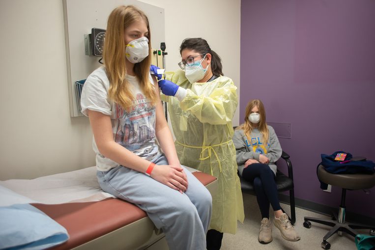 De Amerikaanse Isabelle King (14) krijgt een dosis van het Moderna-vaccin in Houston. Haar tweelingzus Alexandra kijkt toe. Beeld HH / The New York Times Syndication