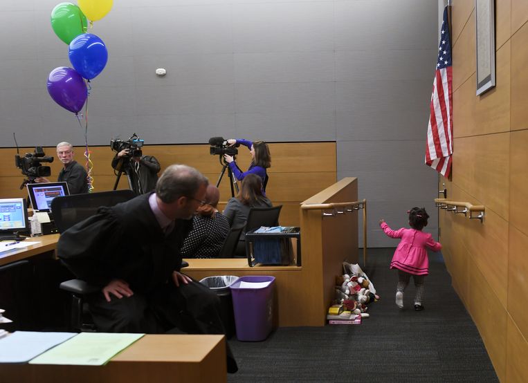 De tweejarige Sierra Jean Haggerty Meyer rent door de rechtszaal van magistraat Howard Bartell tijdens de 14e jaarlijkse adoptiedag van Denver in het Lindsey-Flanigan Courthouse in Colorado. Beeld Denver Post via Getty Images