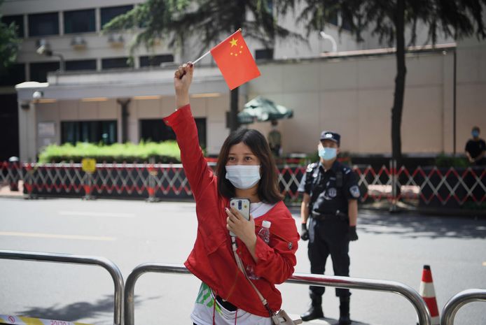 Een vrouw zwaait met een Chinees vlaggetje voor het Amerikaanse consulaat in Chengu.