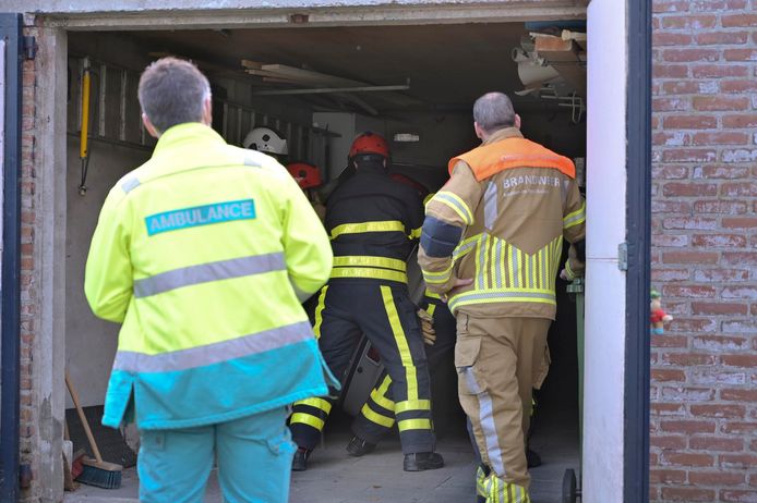 De auto wordt door de brandweer op de wielen gezet in de garage.