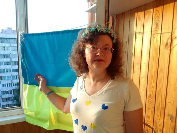 Olga Nazarenko bij een Oekraïense vlag in haar flatje.