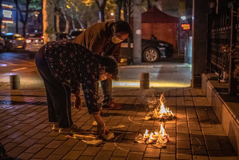 Inwoners van Wuhan verbranden tijdens de jaarlijkse viering van Qingming papieren bankbiljetten ter nagedachtenis van de coronadoden. Beeld EPA