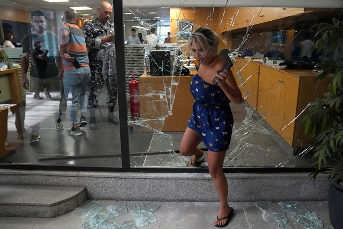 Een bankbediende vlucht in paniek weg doorheen het gebroken glas.