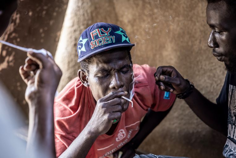 Jonge mannen roken lange dunne sigaretten waarin een mix van marihuana en heroïne zit. Ook het zeer verslavende crack-cocaïne wordt veel gebruikt in Abidjan, de grootste stad van Ivoorkust. Beeld Sven Torfinn