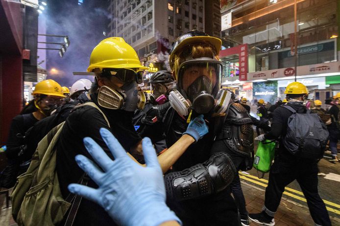 Een hulpverlener gebaart naar mensen die met traangas bespoten zijn in Hongkong.