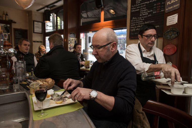 Een gast in restaurant Le Mesturet eet een bavette aan de bar. Achter hem chef Alain Fontaine. Beeld Bart Koetsier