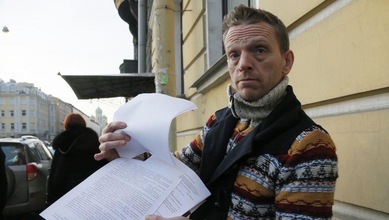 Greenpeace-acticist Mannes Ubels laat journalisten zijn papieren zien voor het immigratiekantoor in St. Petersburg Beeld ap