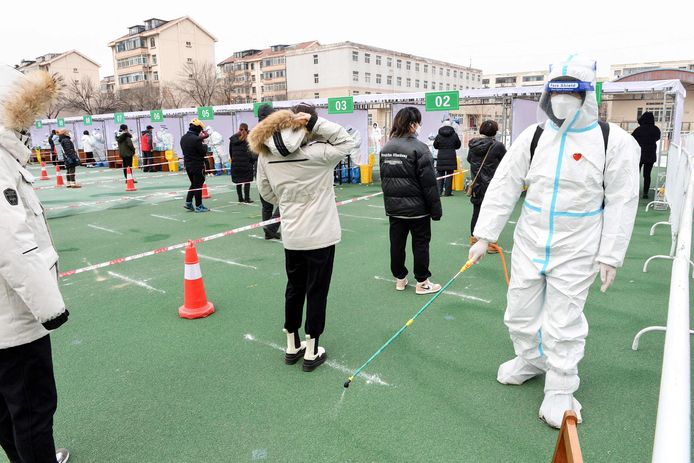 Een man ontsmet terwijl mensen in de rij staan tijdens een massale testcampagne in de stad Tianjin. Beeld van vorige week.