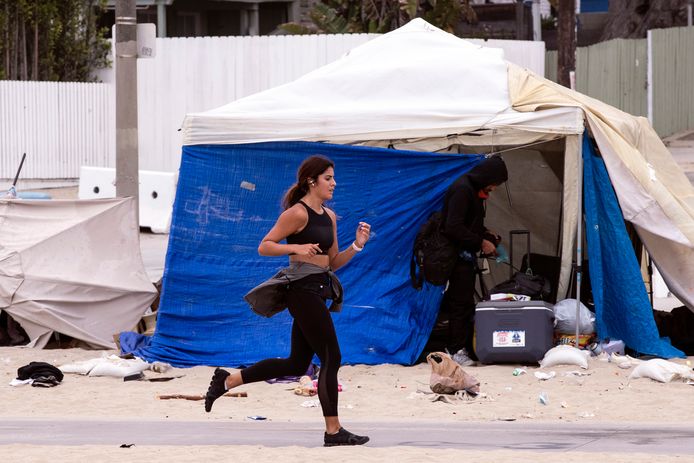 Een joggende vrouw passeert een tentenkamp in Venice Beach, ten oosten van Los Angeles.