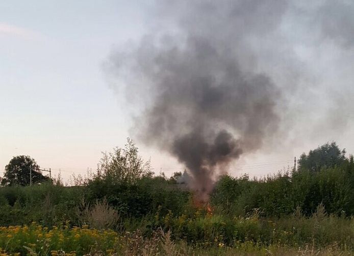 Restanten van de brandende vluchtwagen nabij het spoor.
