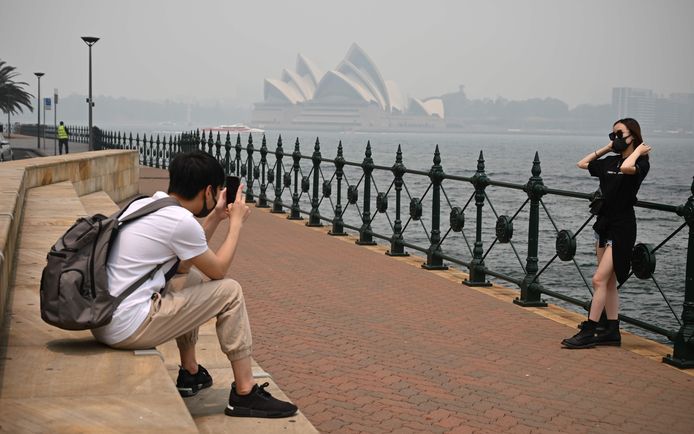 Toeristen maken foto's in Sydney terwijl ze mondmaskers dragen.