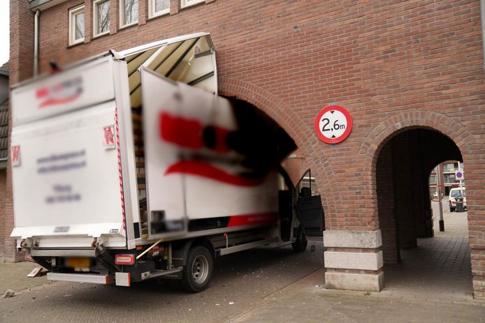 Een bestelbus zit klem in een doorgang onder woningen in Helmond. Daarbij raakten de poort en de bestelbus beschadigd.
