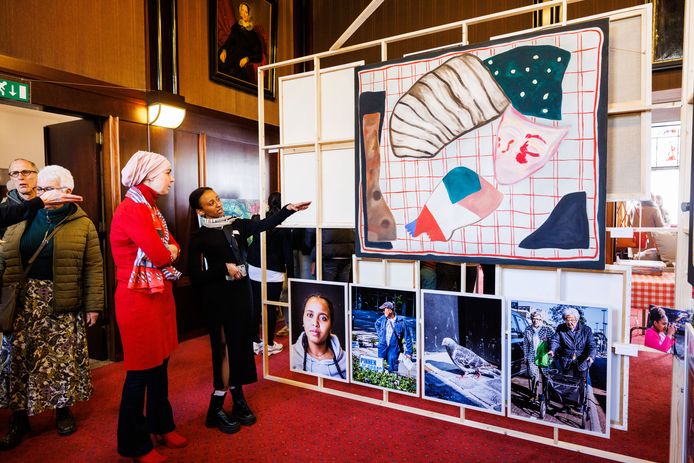 Bij de expositie in het raadhuis kijkt wethouder Esma Lahlah  met Lidia naar het schilderij dat de Eritrese gemaakt heeft.