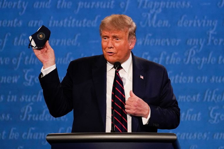 Trump houdt een mondkapje omhoog tijdens het debat met Biden eerder deze week in Ohio. Beeld AP