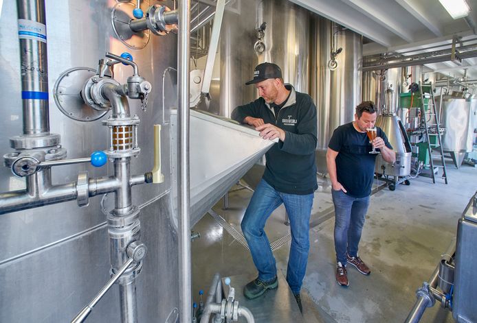 Brouwmeester Frans Schamp tuurt in de brouwketel, terwijl Alwin Houwing een slok bier proeft. De twee brengen D'n Schele Os terug op de markt.