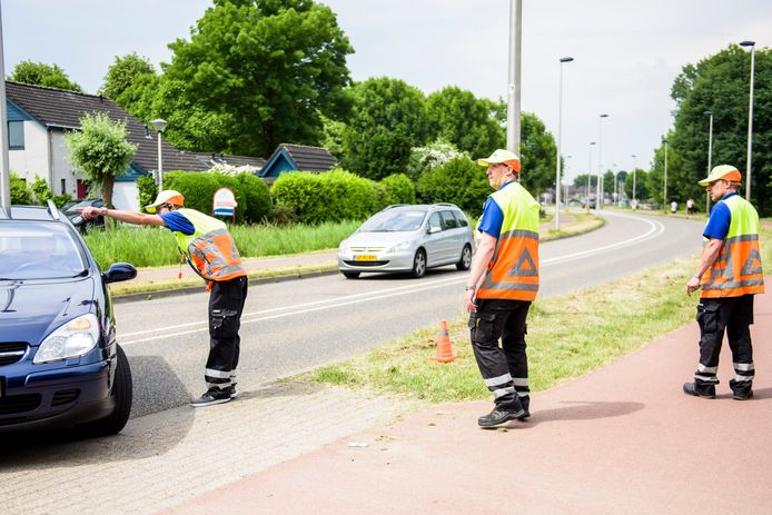 Rick Verlijsdonk (midden) en Wim Hendriks (rechts) aan het werk in Mierlo-Hout. Roel Verlijsdonk (links) praat met een automobilist.