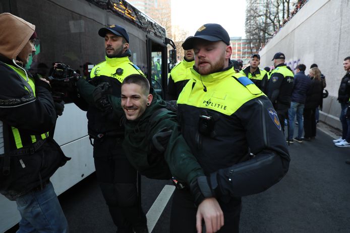 Een glimlachende demonstrant wordt in de bus gezet.