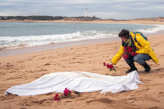 Een vrouw legt bloemen bij het lichaam van een migrant op een strand in Cadiz. Spanje is voor steeds meer vluchtelingen het land om te bereiken.