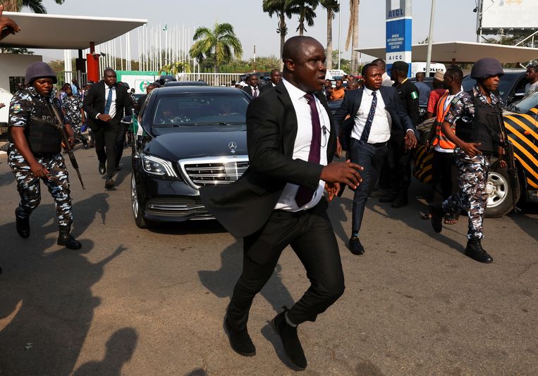 Agenten en beveiligers rennen woensdag mee met de auto van de tot president van Nigeria uitgeroepen Bola Tinubu. Beeld Reuters