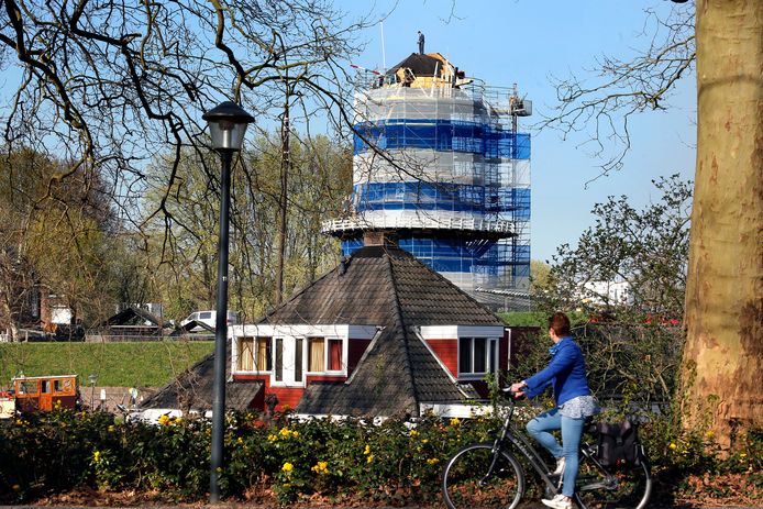 Een dakdekker staat boven op de kap van korenmolen Nooit Volmaakt in Gorinchem.