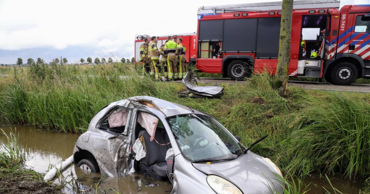 Auto in de sloot na botsing tegen boom; traumahelikopter landt bij ongeval.