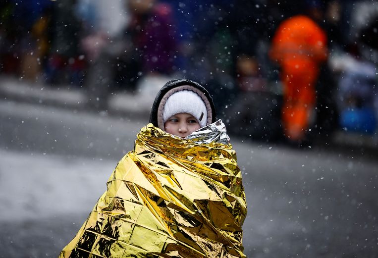 Een vluchteling beschermt zichzelf tegen de kou aan de grens met Polen.  Beeld REUTERS