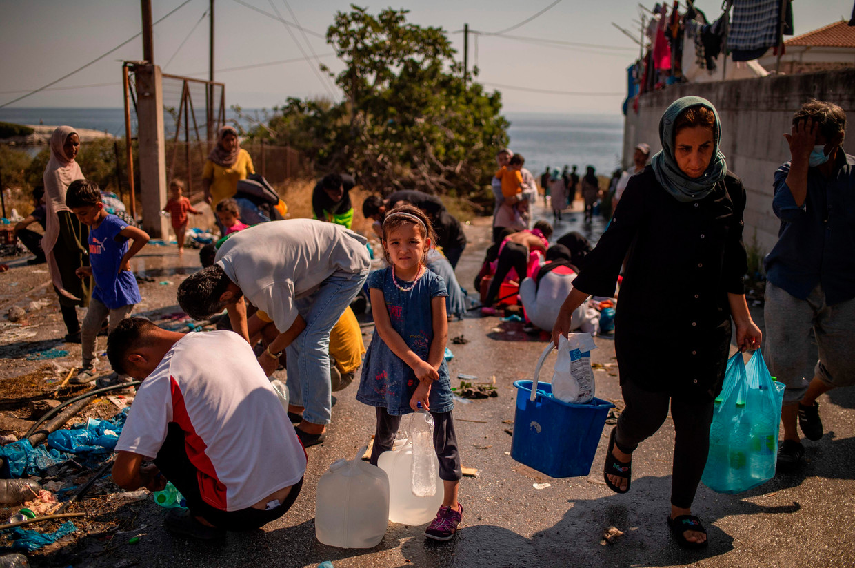 Een meisje wacht tot ze haar jerrycans met water kan vullen, vlakbij een tijdelijk kamp dat is opgezet nadat Moria in vlammen opging.  Beeld AFP