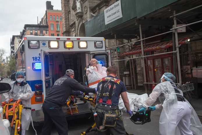 Een coronapatiënt wordt door een ambulance opgehaald in New York.