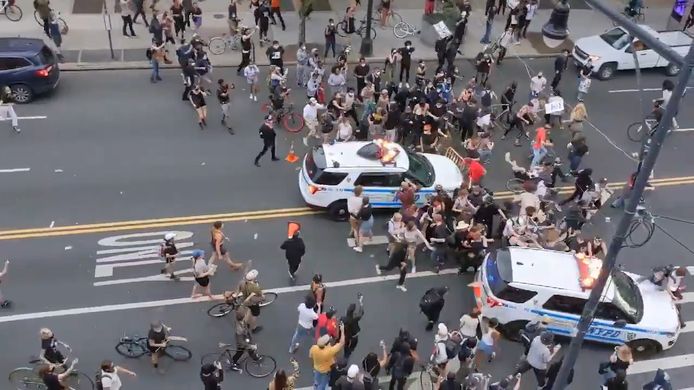 Politiewagens rijden in op betogers in New York.
