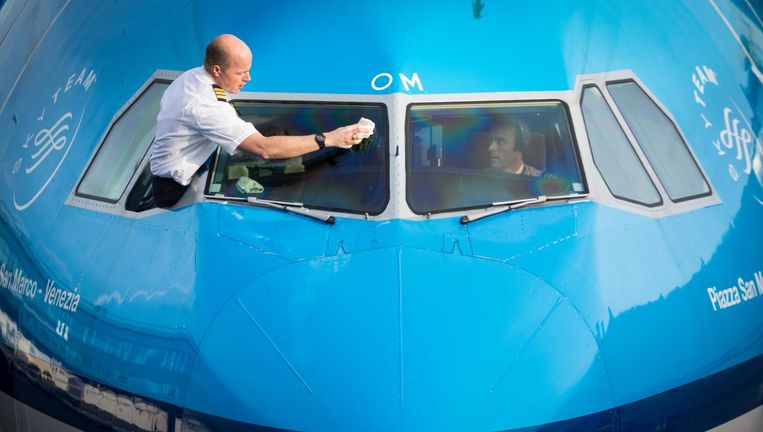Een piloot van KLM maakt de ruit van zijn cockpit schoon. Beeld David van Dam