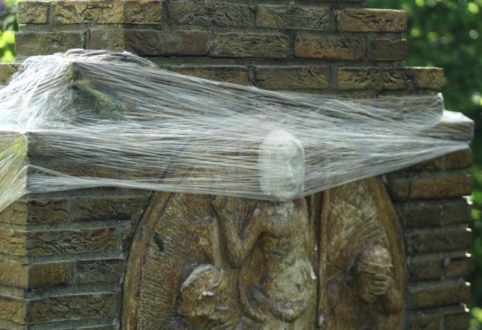 Een reep plastic houdt een net aangebracht Christuskopje op z'n plaats en beschermt het (tijdelijk) tegen regen en wind.
