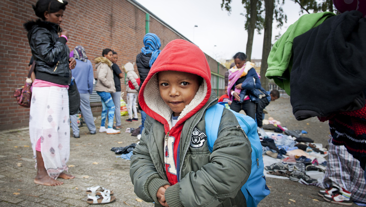 Vluchtelingen zoeken in Rotterdam kleding uit die buurtbewoners naar een opvangcentrum hebben gebracht. Beeld anp