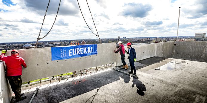 Wethouder Eddie Förster (rechts) helpt met het plaatsen van de laatste betonplaat die symbolisch het hoogste punt van de toren Eureka mag zijn.
