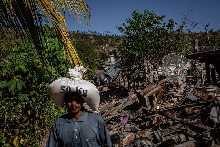 Een man loopt door de ravages van huizen na de aardbeving in Pemenang. Beeld Getty Images