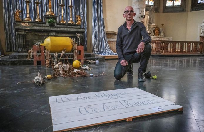 Kunstenaar Rik Moermans bij zijn installatie in de Sint-Pieterskerk, die mensen moet doen nadenken over het lot van vluchtelingen.