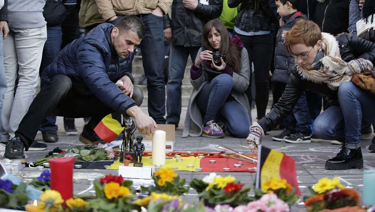 Bloemen en kaarsen worden geplaatst op het Beursplein in Brussel. Beeld afp