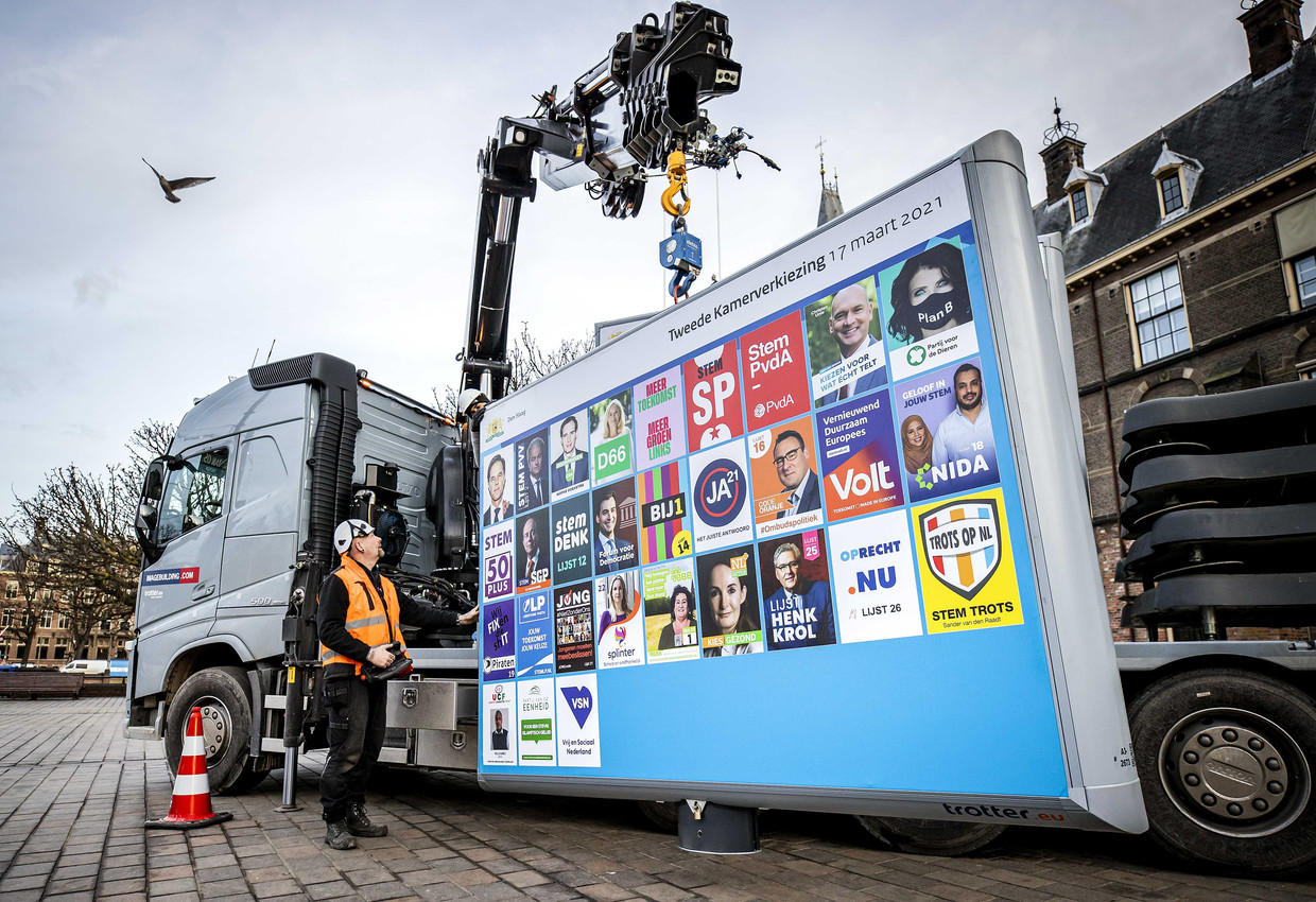 Medewerkers plaatsen een verkiezingsbord voor de Tweede Kamerverkiezingen op het Buitenhof.  Beeld ANP