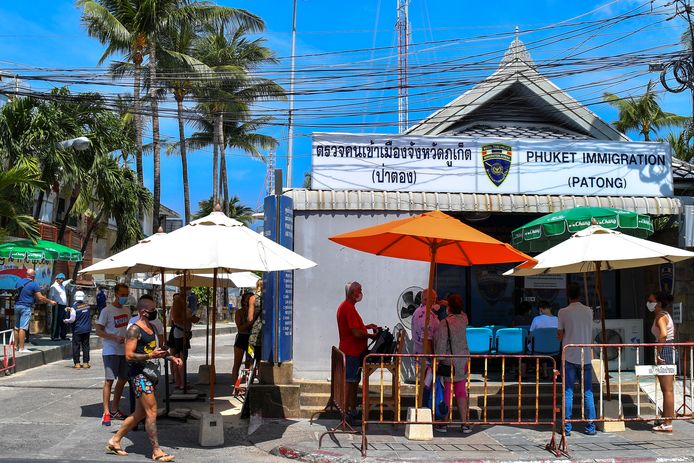 Toeristen wachten aan een immigratiekantoor in Phuket. Vanaf zaterdag gaan de hotels in de provincie dicht.