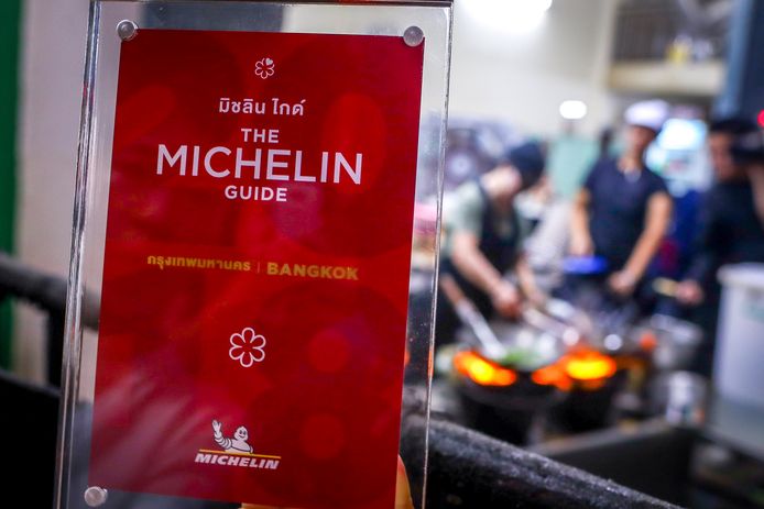 epa06374576 A waitress shows the framed award star from Michelin as 70-year-old chef Jay Fai (R) cooks on coal powered stoves at her Michelin star restaurant in Bangkok, Thailand, 08 December 2017. The Raan Jae Fai restaurant, run by Chef Jay Fai and popular both for Jay Fai's oversized glasses as well as its fried drunken noodles and crab omelette (1,000THB or 26 euro), was awarded on 07 December 2017 a Michelin star, making it the first street food restaurant in Thailand to be awarded a Michelin star.  EPA/DIEGO AZUBEL