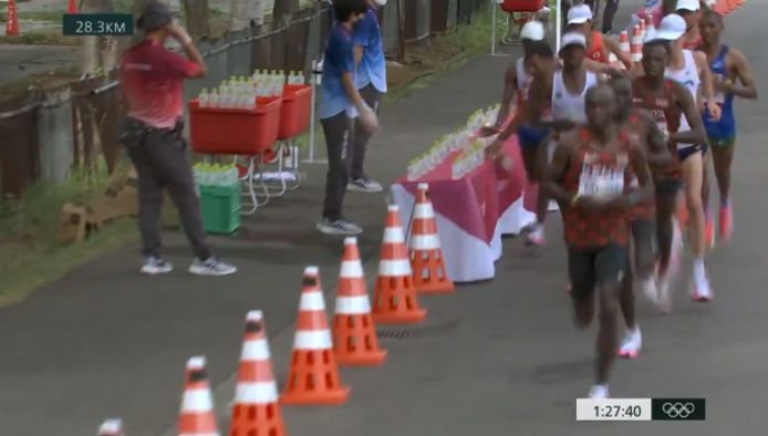 In de buik van de kopgroep duwt Morhad Amdouni een volledige rij flesjes water van tafel.