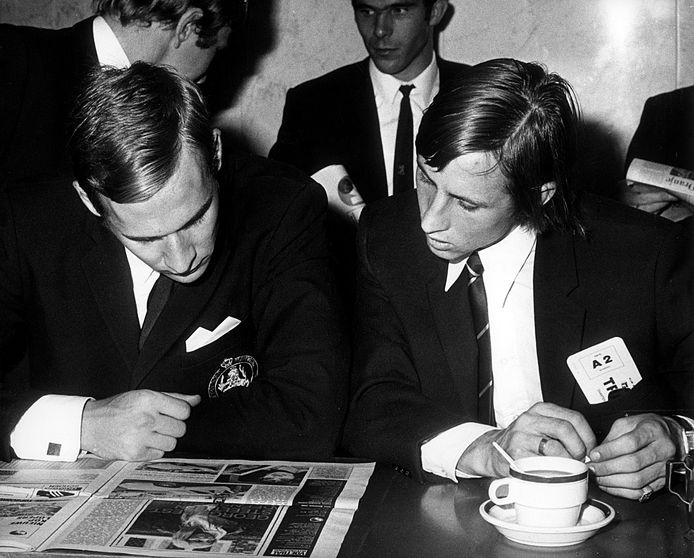 Jan van Beveren en Johan Cruijff lezen samen het laatse voetbalnieuws in 1969 voor het vertrek naar Polen op Schiphol. foto ANEFO