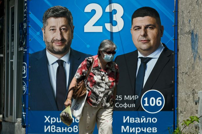 A woman walks past a poster of Hristo Ivanov (L) and Ivaylo Mirchev of the electoral alliance 'Democratic Bulgaria' in Sofia on July 8, 2021, ahead of the parliamentary elections. - Bulgaria holds snap parliamentary elections on July 11, 2021 after failing to form a government after the last vote in the spring 2021. (Photo by Nikolay DOYCHINOV / AFP)