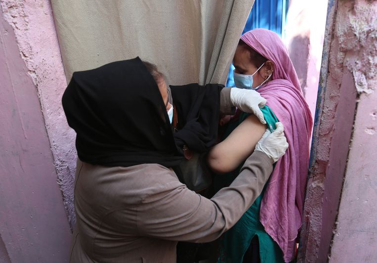 Een Pakistaanse vrouw krijgt dinsdag een boosterprik tegen het coronavirus. Overheidsteams gaan in het Zuid-Aziatische land van deur tot deur om mensen in te enten. Beeld EPA