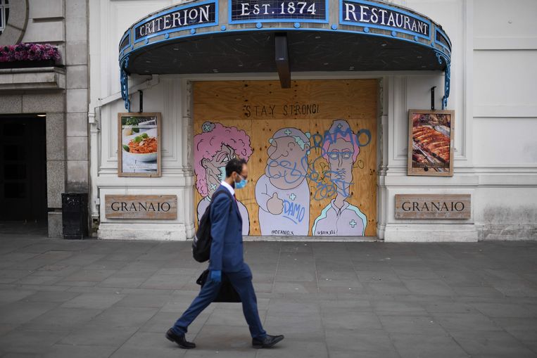 Een man wandelt voorbij een gesloten restaurant in het centrum van Londen. Beeld AFP