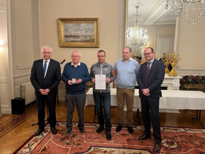 Voorzitter Geert Messiaen, kalenderverantwoordelijk Roby Devlies en secretaris Alexander Hanssens kregen de medaille en oorkonde uit handen van gouverneur Carl Decaluwé en de provinciegriffier